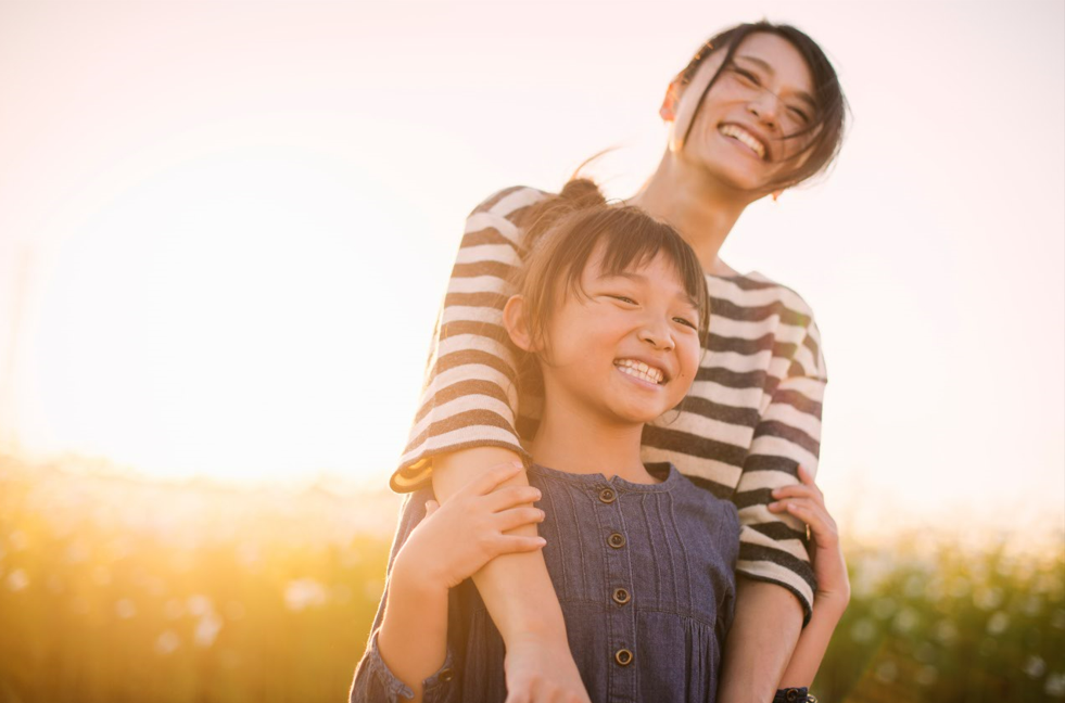 Mom and daughter smiling in open field