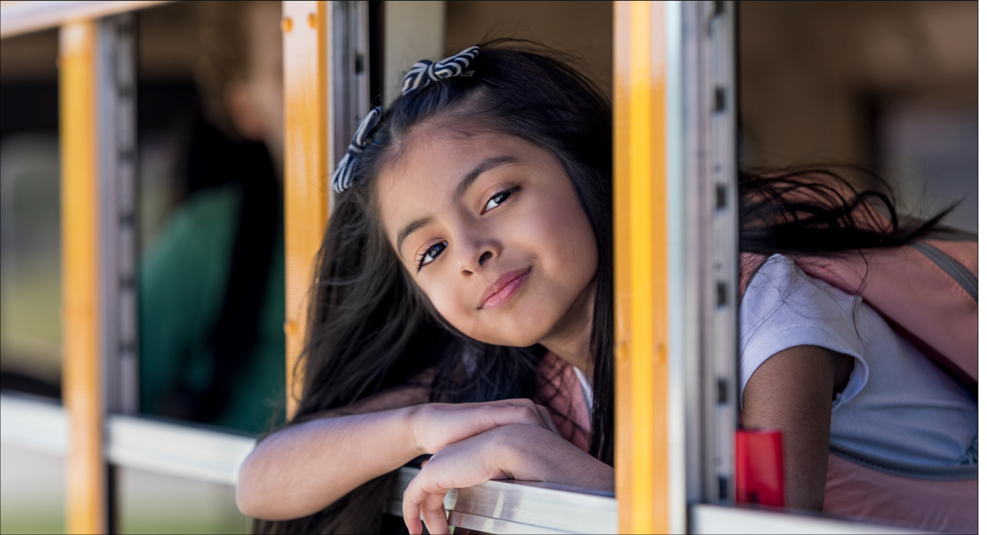 Young female student looking out window of school bus.