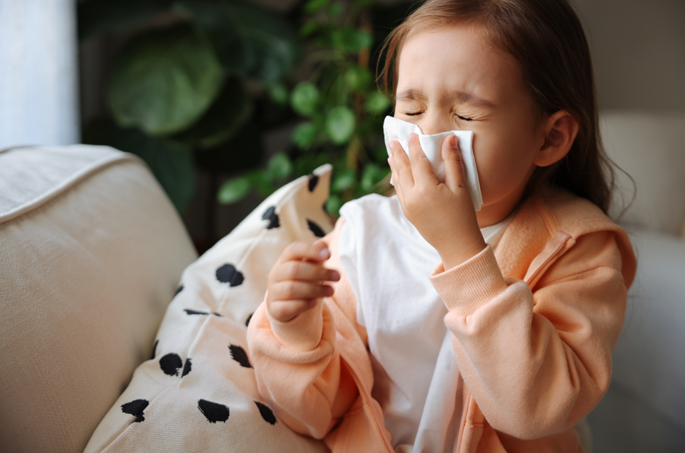 Young girl sneezing into tissue