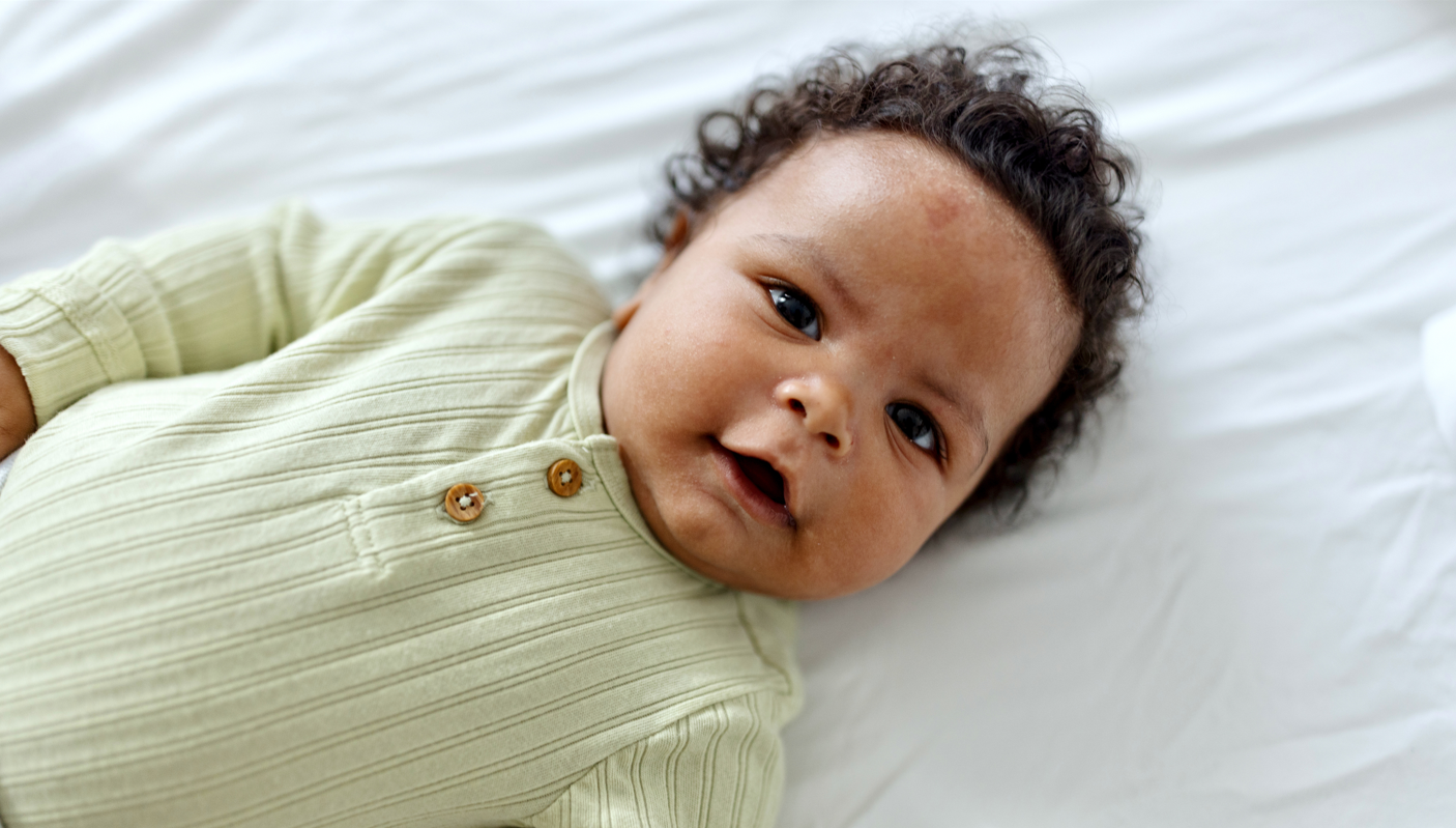 Infant boy laying on back in crib.