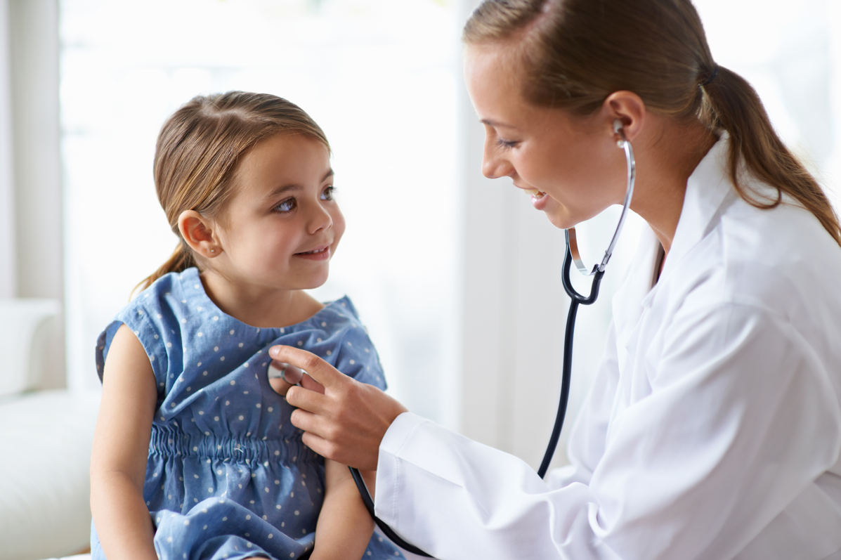 Doctor listening to young girl's heart with stethescope.
