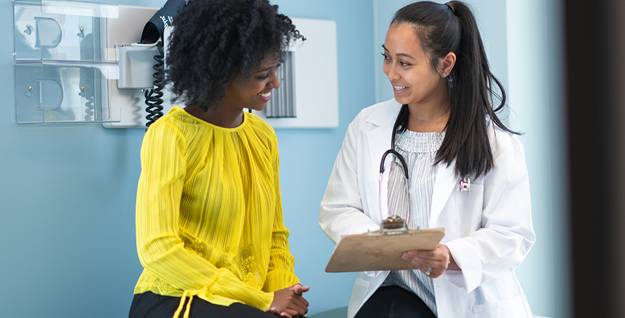 Young woman talking with doctor in exam room